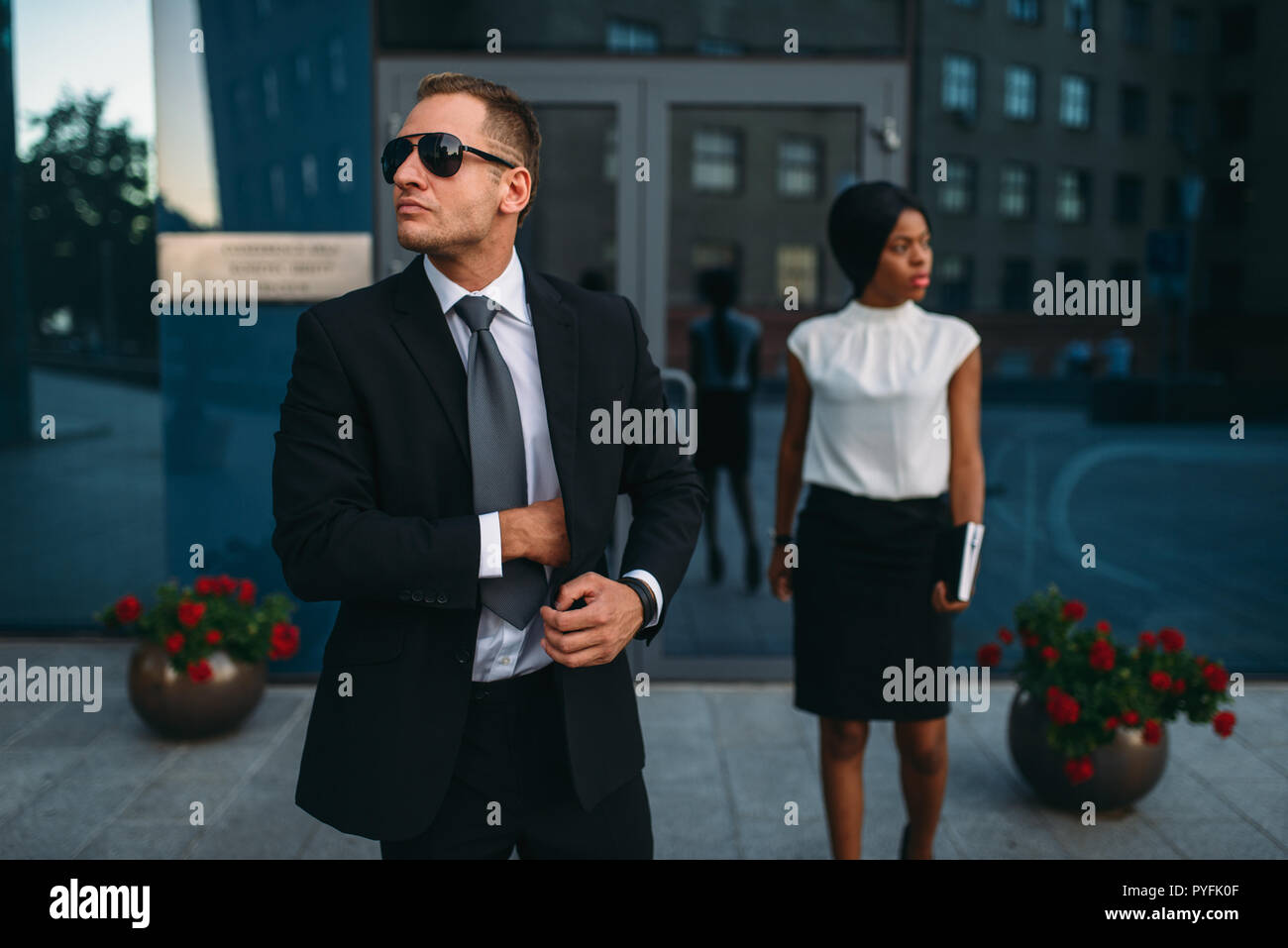 Leibwächter in Anzug und Sonnenbrille, weiblich VIP-Kunde für den Hintergrund. Security Guard ist eine riskante Beruf, professionelle Bewachung, business Personen Protein Stockfoto