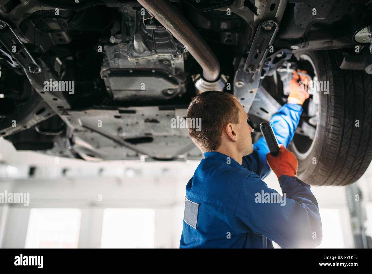 Mechaniker mit Lampe prüft Auto Bremsschläuche, reparieren lassen. Reifen  Service, Wartung des Fahrzeugs Stockfotografie - Alamy