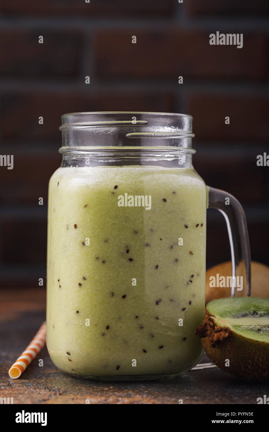 Hausgemachten Smoothie aus reifen Kiwis in einem Glas mit Obst auf den Tisch gestellt Stockfoto
