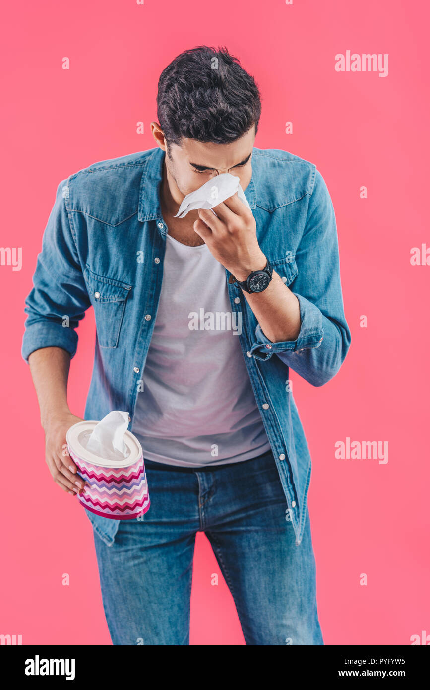 Junger Mann mit Tissue Box weinen und wischen Nase isoliert auf Rosa Stockfoto