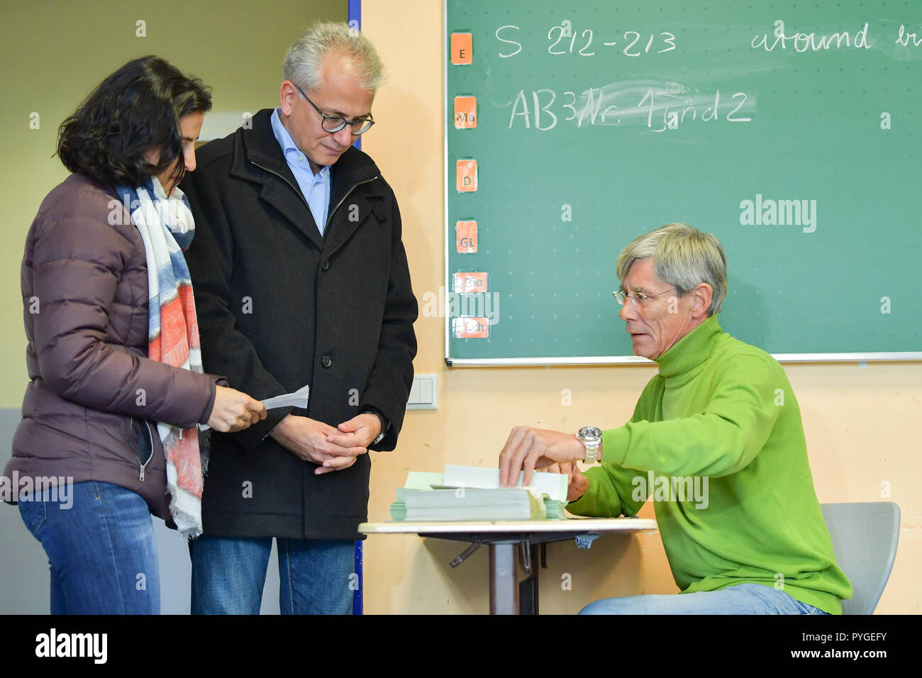 Offenbach, Deutschland. 28 Okt, 2018. Tarek Al-Wazir (M), der Hessischen Wirtschaft und Verkehr Minister und Spitzenkandidat von Bündnis 90/Die Grünen, und seine Frau Bushra Barakat wird im Wahllokal der Ernst-Reuter-Schule stimmen. Foto: Uwe Anspach/dpa/Alamy leben Nachrichten Stockfoto