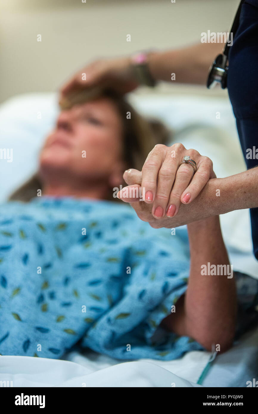 Arzt und eine Krankenschwester Pflege für einen Patienten in einem Hospiz Krankenhaus als Patient nähert sich dem Ende ihrer Lebensdauer. Stockfoto