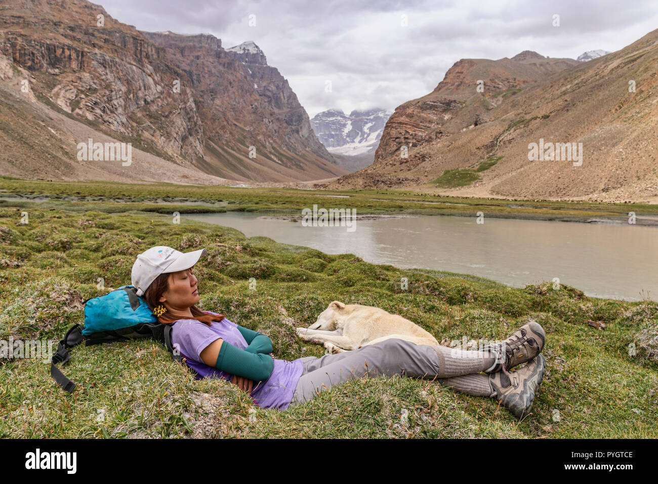 Trekker nap mit lokalen Hund in Engels Peak Hill, Langar, tadschikischen Wakhan, Pamir, Tadschikistan Stockfoto