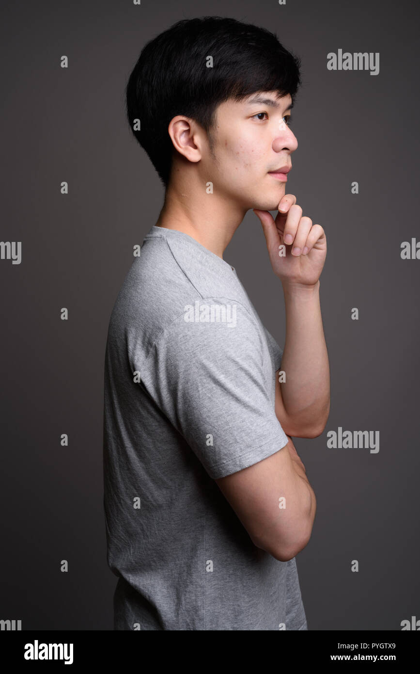 Profil anzeigen von Jungen gut aussehenden asiatischer Mann denken Stockfoto