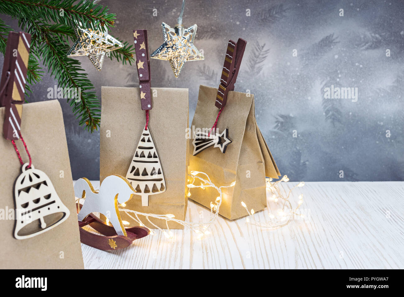 Papier christmas gift bags mit dekorativen Holz- Pin auf silbernem Hintergrund mit Fir Tree Branch Stockfoto