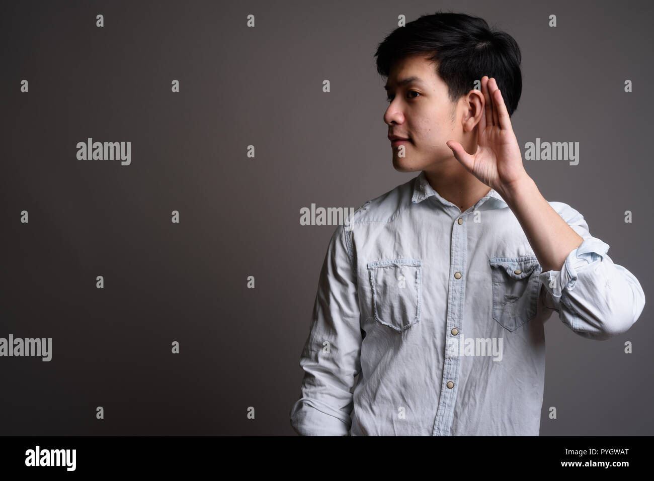 Studio Portrait von jungen hübschen Asiatische Geschäftsmann klistening Stockfoto