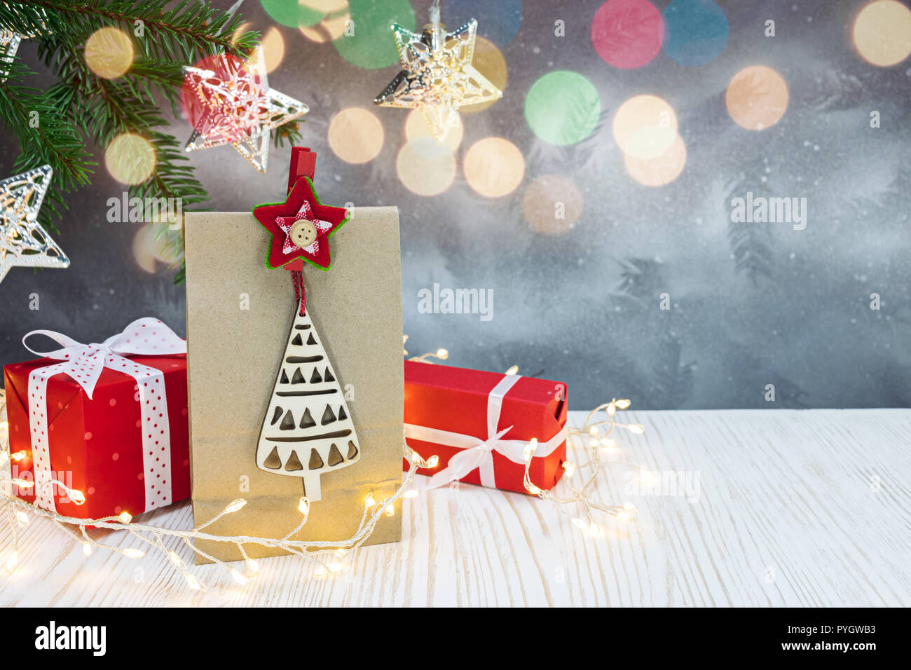 Red Geschenkboxen, Papier Geschenkbeutel, grüne Tanne Baum, girlande Lichter auf Silber Weihnachten Hintergrund Stockfoto