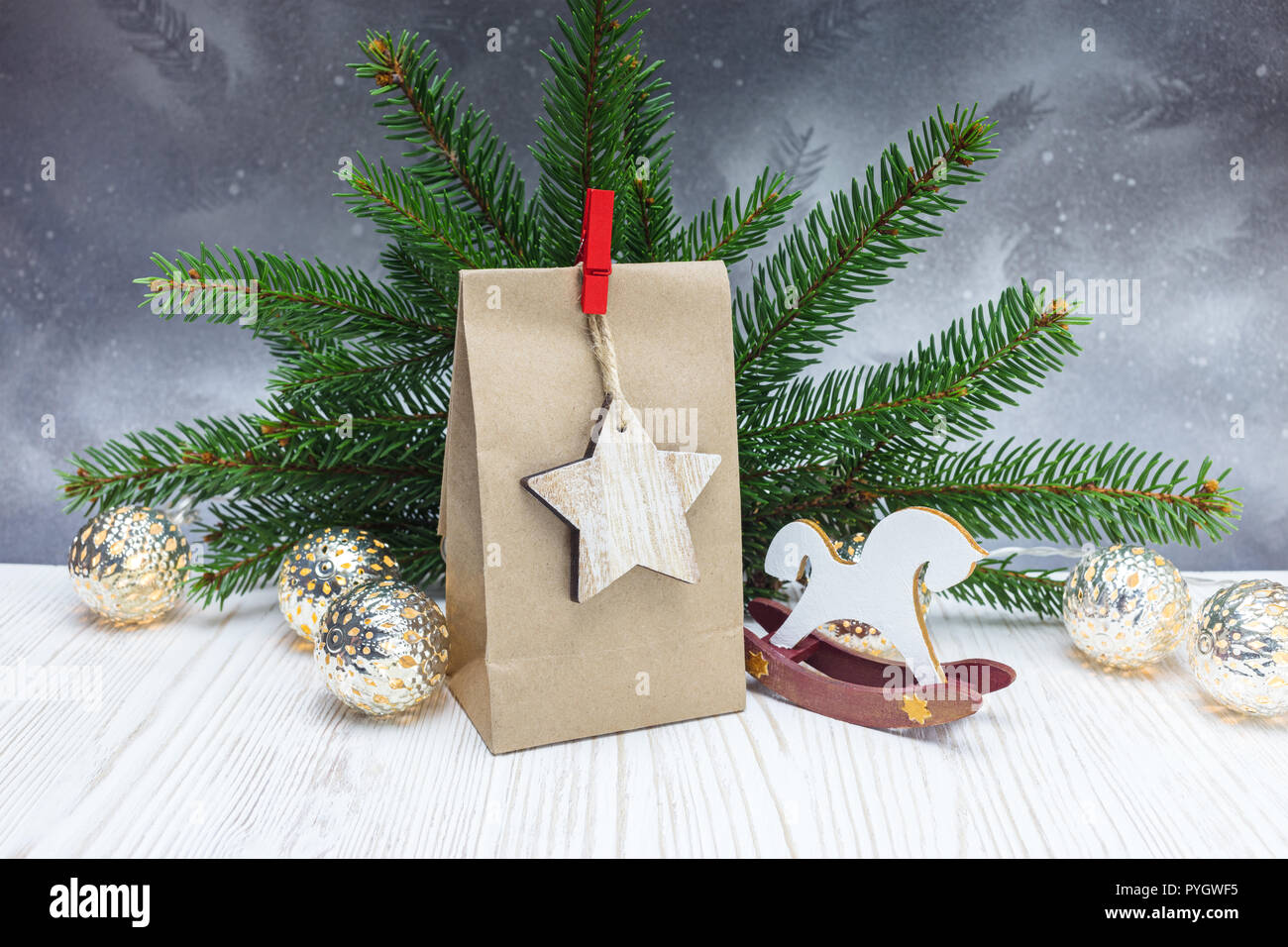 Green Christmas tree branch, Papier Geschenkbeutel, leuchtende Girlande Lichter und hölzerne Pferd Spielzeug auf silbernem Hintergrund Stockfoto