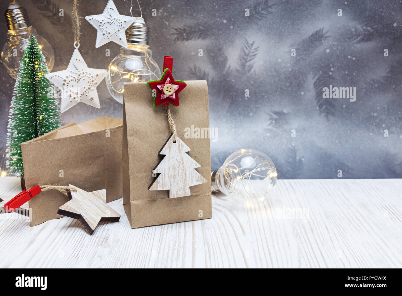 Festliche Weihnachten Hintergrund mit retro Girlande Lampen, handgeschöpftem Papier Geschenkbeutel mit Holz Dekorative Stift und kleine Tanne Stockfoto