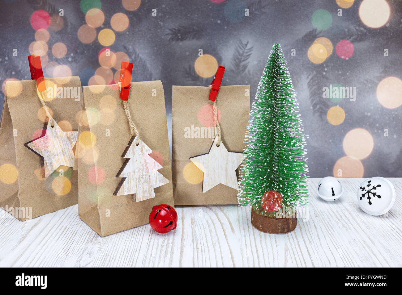 Papier Geschenk Taschen und kleine Weihnachten Tannenbaum auf weißen Holzmöbeln im Landhausstil Bretter gegen silber hintergrund Stockfoto