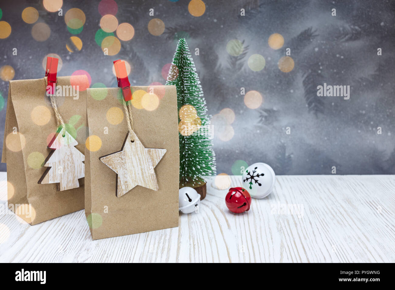 Christmas jingle bells und Papier Geschenkbeutel mit kleinen Tannenbaum auf festliche silberner Hintergrund Stockfoto