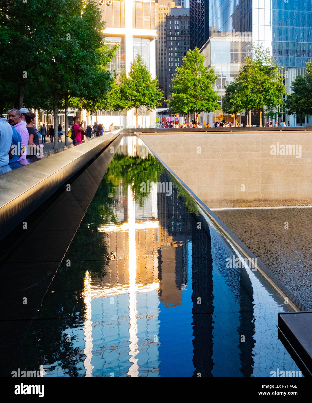 Die Sonne, die auf einem Gebäude scheint, hebt ein Kreuz an den 9/11 World Trade Center Memorial Founneons in Lower Manhattan, New York City hervor Stockfoto