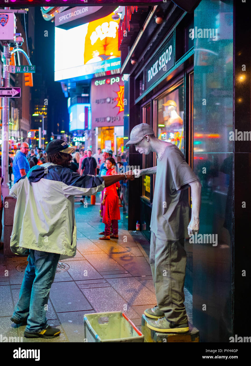 Ein lokaler Mann pumpt einen Straßenkünstler auf dem Times Square, Midtown, Manhattan, in einer geschäftigen Nacht vor den Neonlichtern Stockfoto