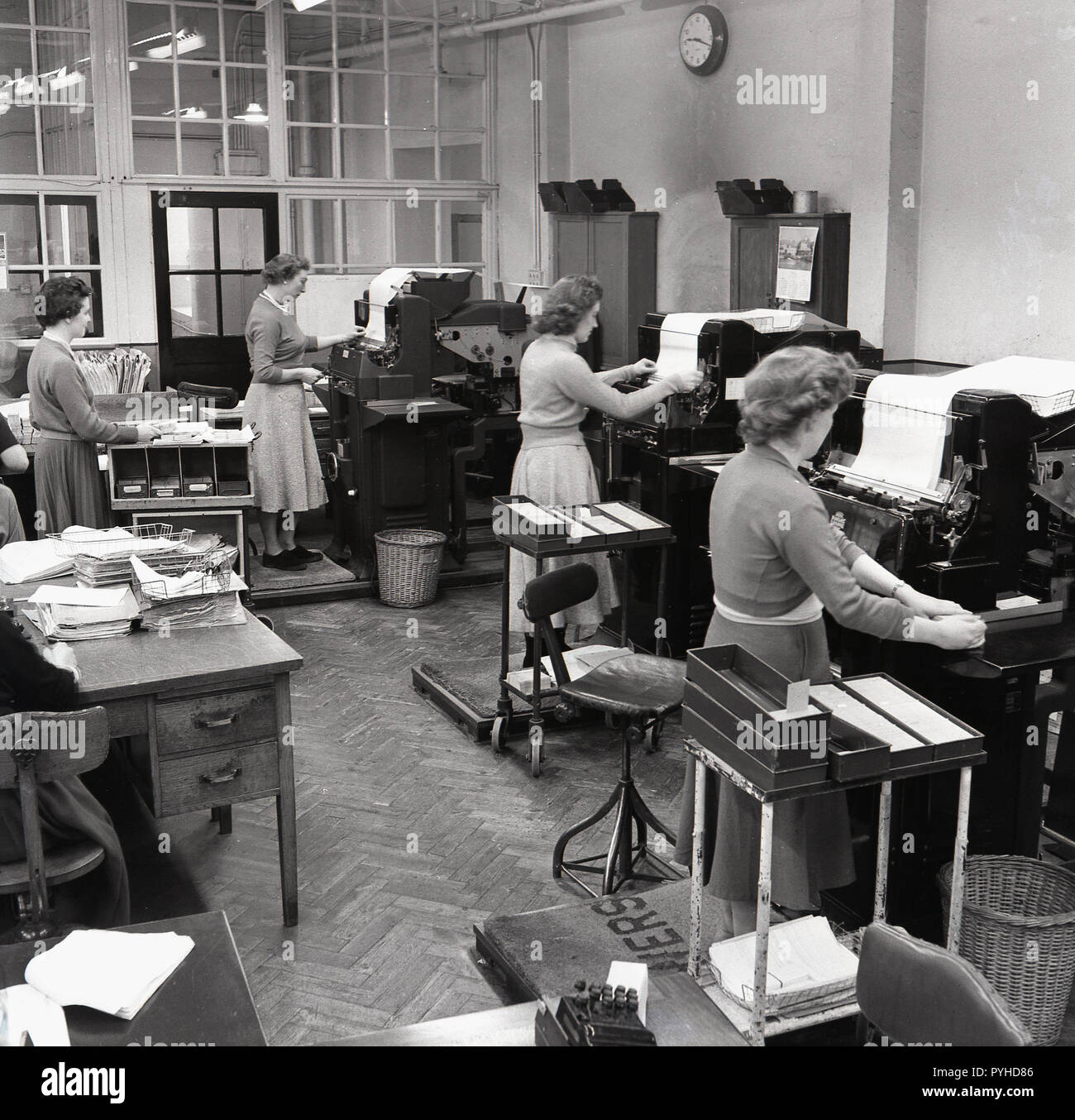 1950, historische, Frauen mit großen industriellen hinzufügen oder die Berechnung der Maschinen in einem Büro, England, UK Personal. In größeren Unternehmen diese industriellen sortierte Maschinen, die kombiniert grundlegende Berechnung mit Druck für die Abrechnung und Rechnungsstellung verwendet wurden. Stockfoto