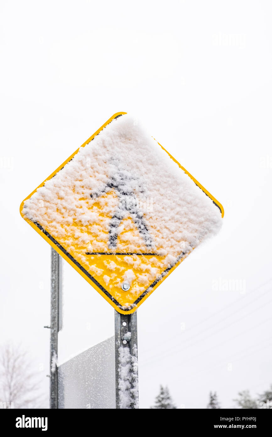 Pedestrial Kreuzung Zeichen bedeckt mit nassen Neuschnee. Konzept für den ersten Schnee oder rutschige Bedingungen. Stockfoto