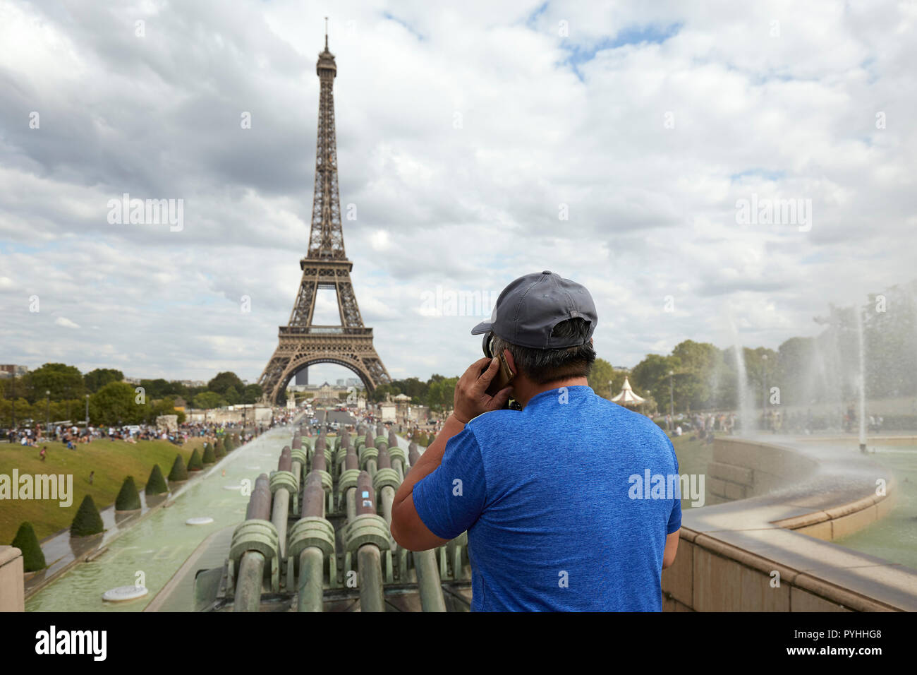 Paris, Ile-de-France, Frankreich - ein Mann mit einem Mobiltelefon auf seinem linken Ohr steht über dem Brunnen im Jardins du Trocadéro mit dem Eiffelturm im Hintergrund. Stockfoto