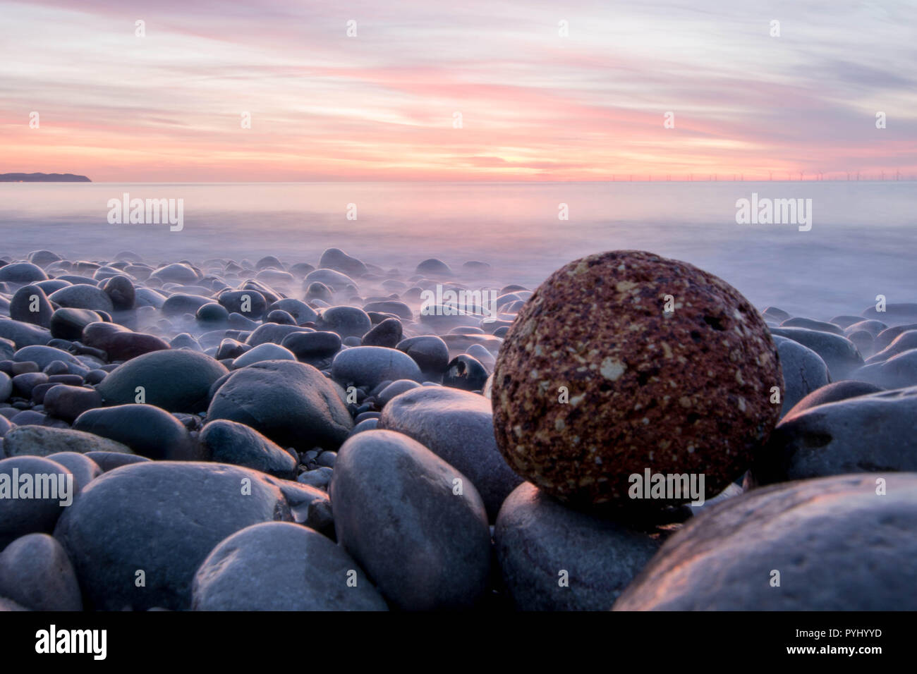 Red Rock auf weißem Kies Sunset Beach - North Wales Stockfoto