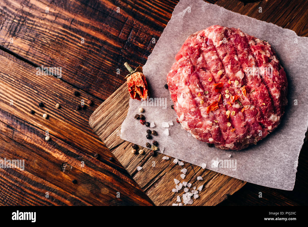 Raw Runde Patty mit Gewürzen auf Wachspapier für Burger. Blick von oben. Stockfoto