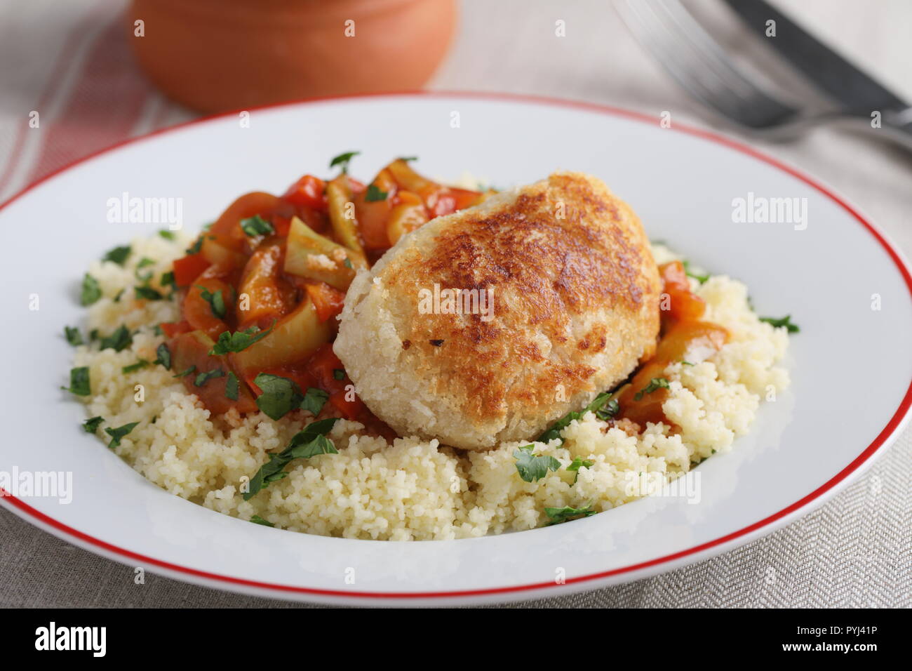 Schnitzel mit Couscous, geschmortem Gemüse und Tomatensauce. Stockfoto