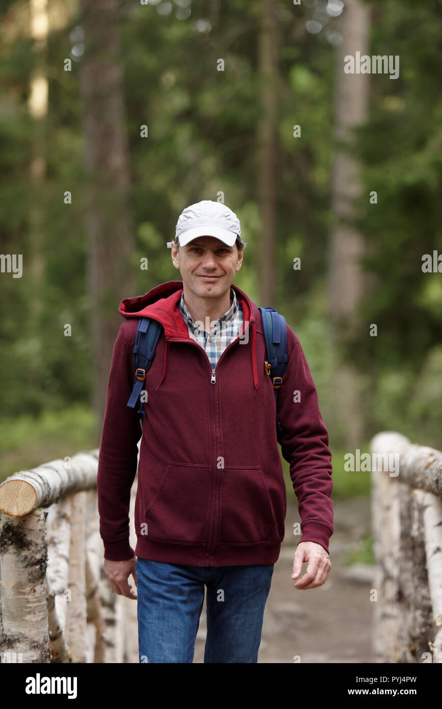 Mann mit Rucksack an der hölzernen Brücke in einem Wald Stockfoto