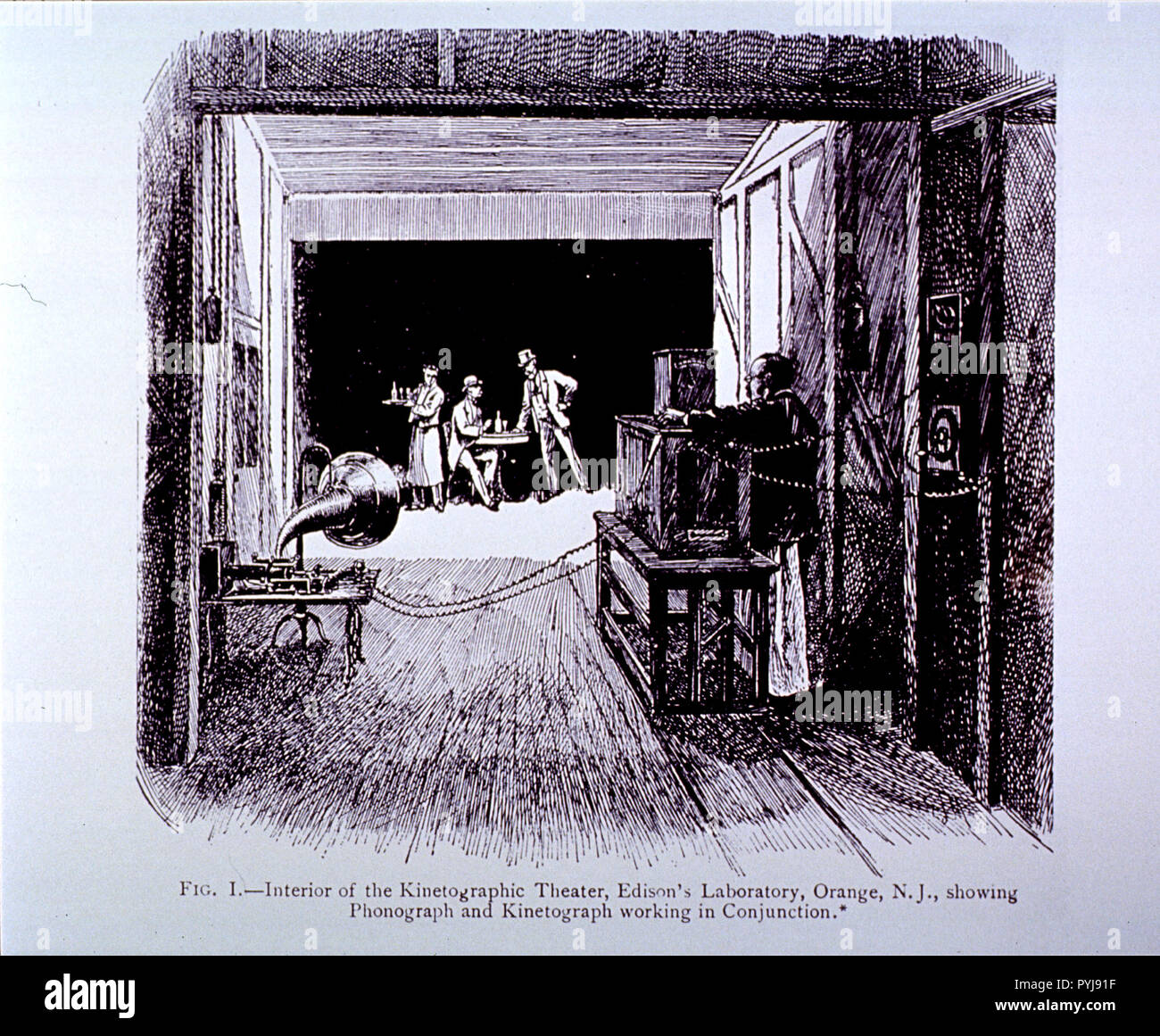 Eine marode Teerpappe shack in East Orange, NJ, im Besitz von Thomas Edison, ist der erste Motion Picture Studio in den Vereinigten Staaten. Auf der Bühne ist ein Kellner neben einem Mann an einem Tisch sitzen, während ein anderer Mann steht. Mit Blick auf die Männer ist eine Holz- Kamera, amtlich kinetograph (Edison nannte es der Hundehütte). Stockfoto