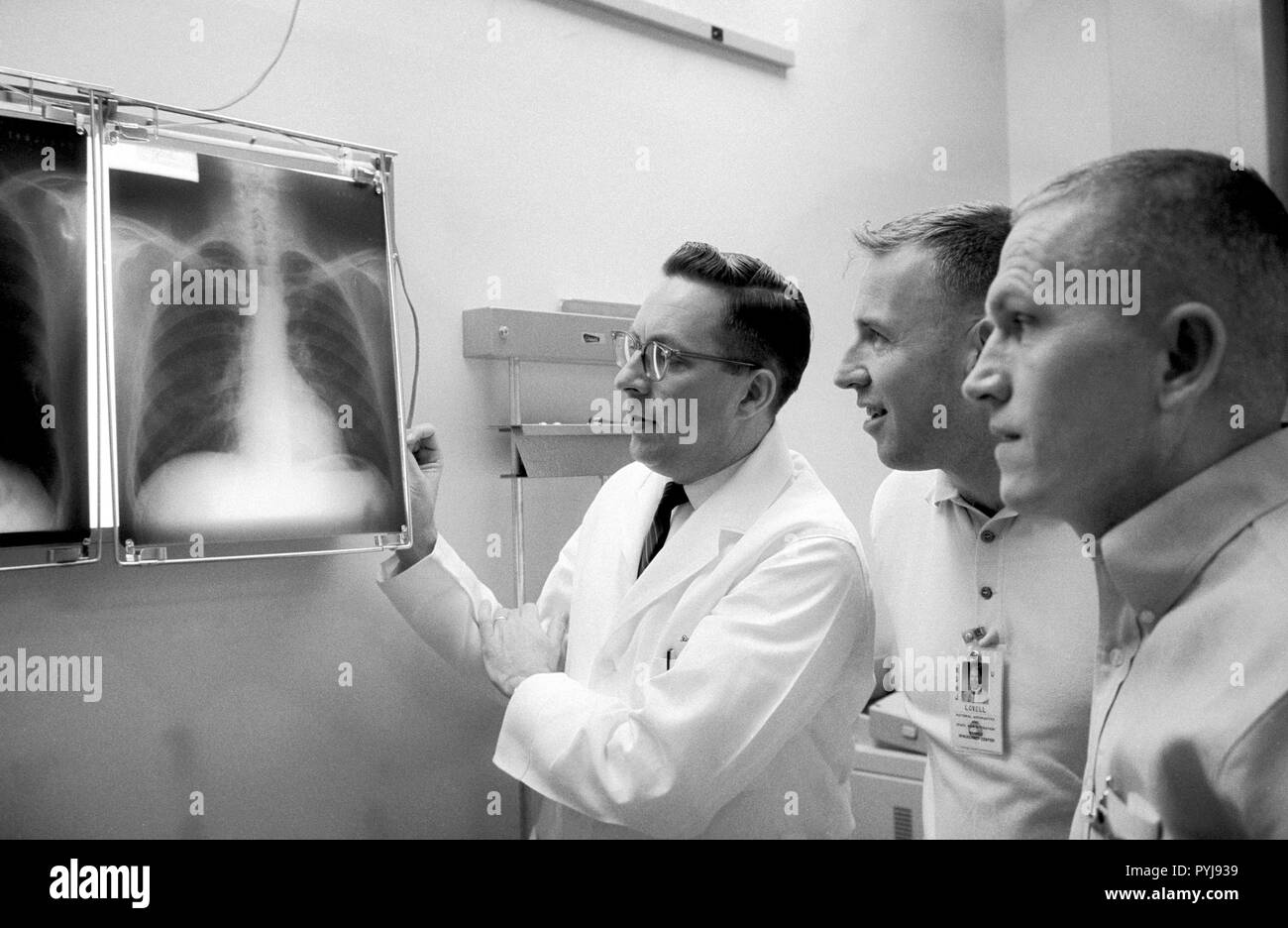 (2 Dez. 1965) --- Dr. Charles A. Berry (links), Leiter der bemannte Raumfahrzeuge Center (MSC) Medizinische Programme, und Astronauten James A. Lovell Jr. (Mitte), Gemini-7 Pilot, und Frank Borman, Gemini-7 Befehl Pilot, untersuchen eine Reihe von Röntgenaufnahmen der Brust während des Preflight physischen genommen. Stockfoto