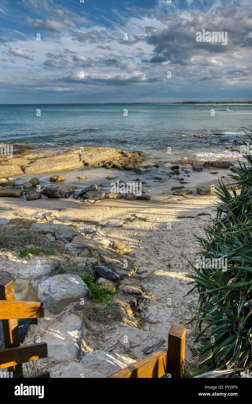 Strand Eingang Foot Prints in Sand weichen Wellen blauer Himmel mit Wolken, Surfer in der Entfernung Stockfoto