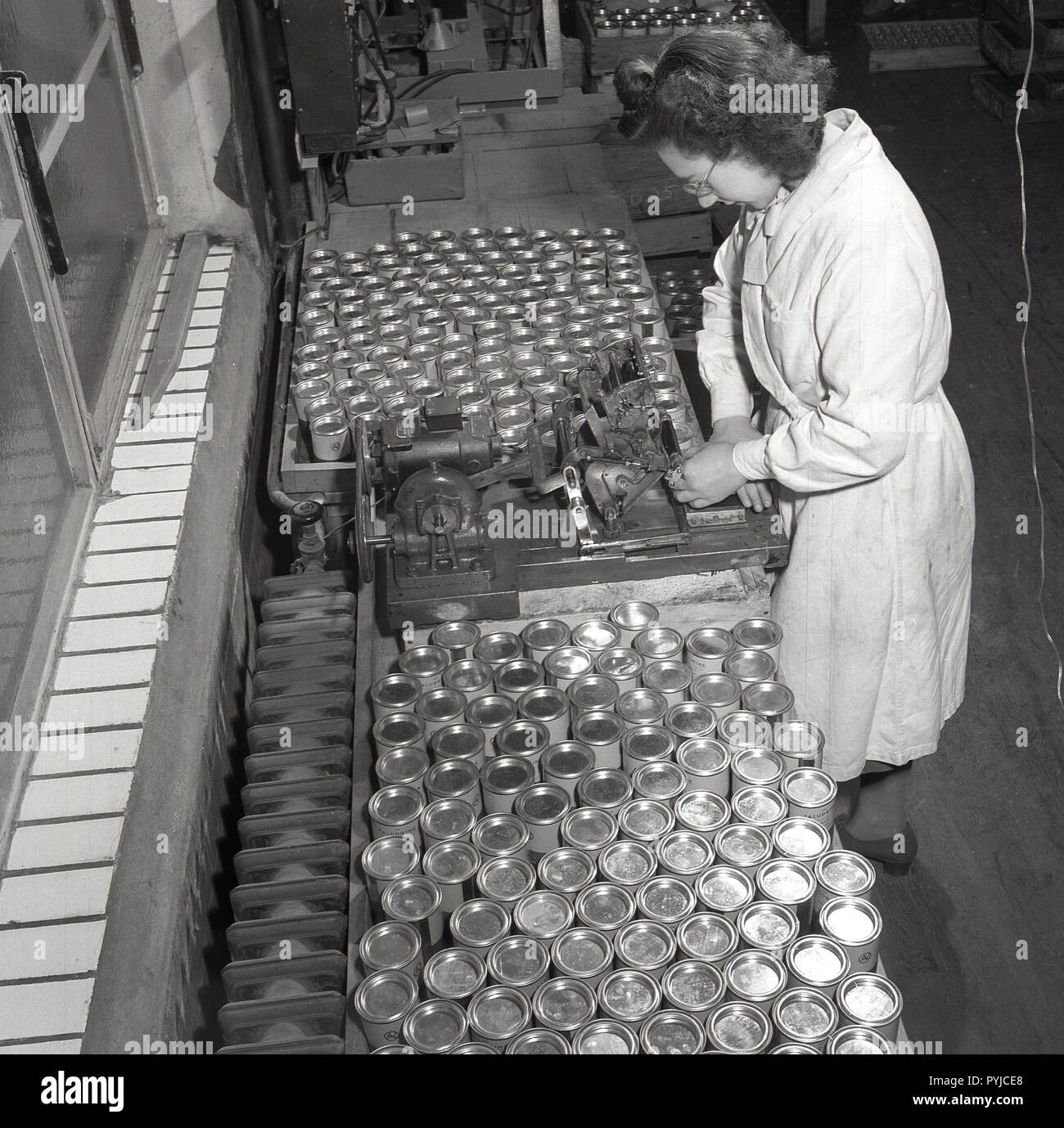 1950, historische, Frau in einer Sattelrobbe (Abdichtung Dosen Praludrine Tabletten an der medizinischen Hersteller und Lieferanten, Arthur Cox & Söhne. Paludrine ist der Handelsname für Proguanil-HCL, einem Medikament zur Behandlung und Malaria zu verhindern und wurde entwickelt, b yone der großen britischen Standort in dieser Ära, Imperical Chemical Industries (ICI). Stockfoto