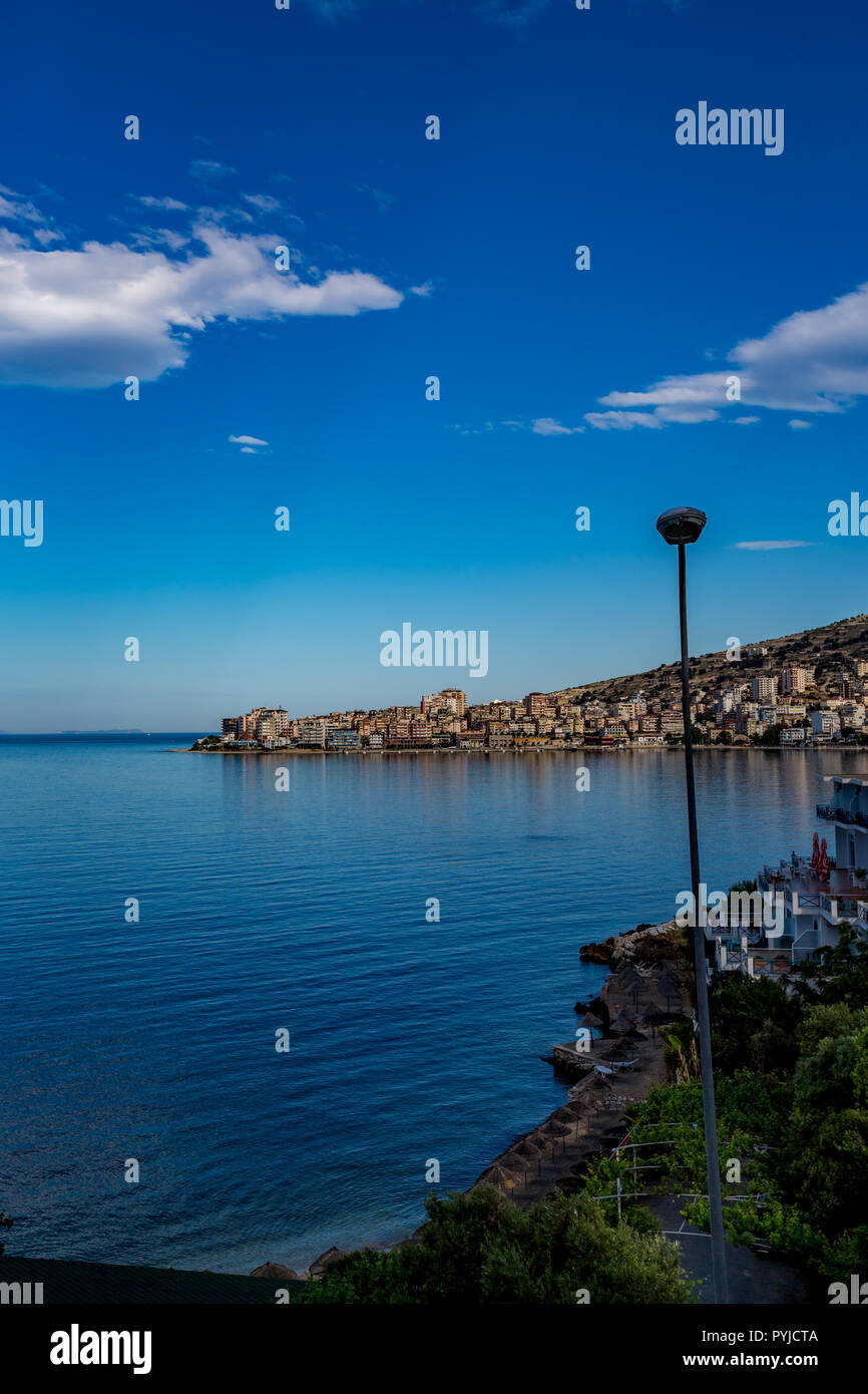 Feder tagsüber Landschaft Foto, stadtbild am schönen Meer Stadt Saranda, Albanien mit kristallklaren Wasser der Adria, blauer Himmel und weiße Wolken Stockfoto