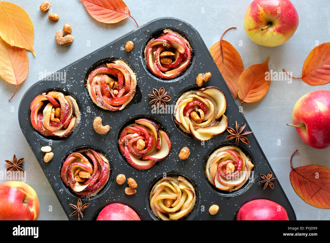 Fach von Apple Rosen in Blätterteig gebacken auf grauem Beton Hintergrund mit Herbstlaub und rote Äpfel Stockfoto