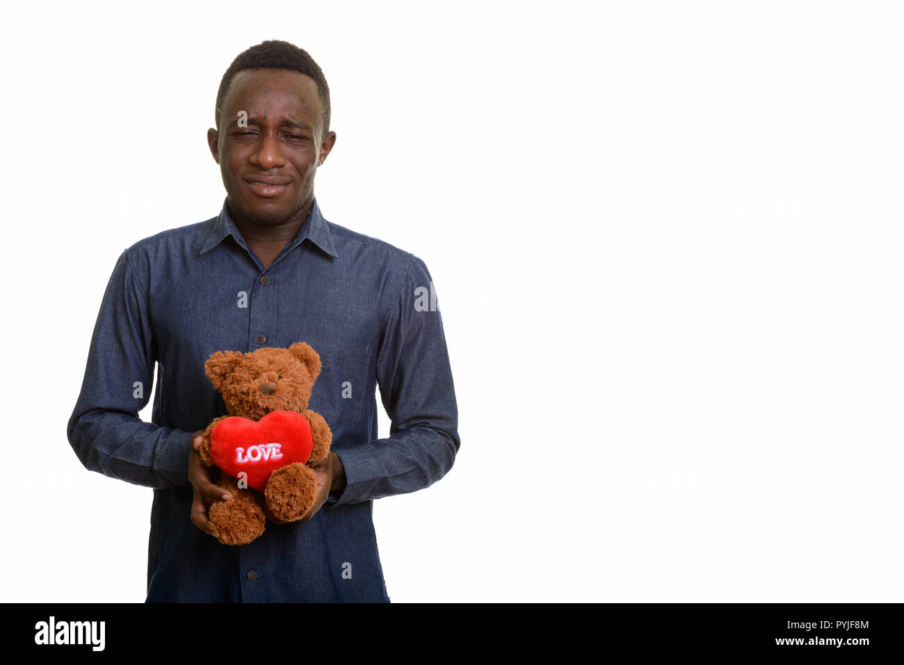 Junge schöne afrikanischer Mann traurig halten Teddybär Stockfoto