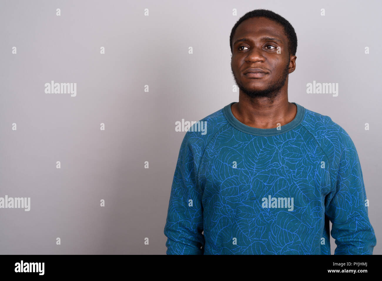 Junge afrikanische Mann trägt blaue Langarm Shirt gegen Grau b Stockfoto