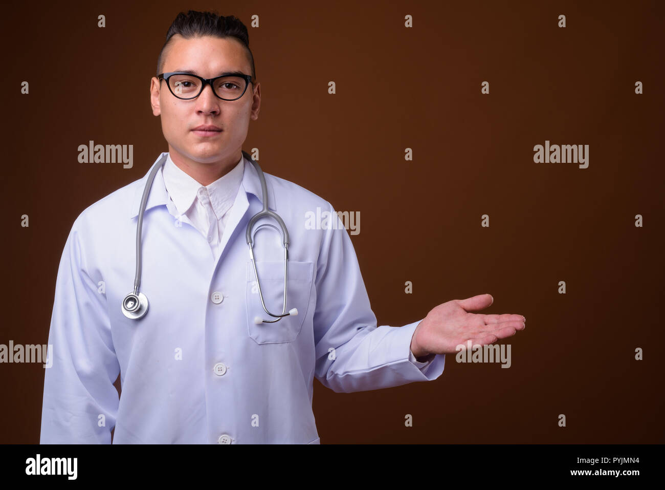 Junge schöne multi-ethnischen Mann Arzt gegen braunen Hintergrund Stockfoto