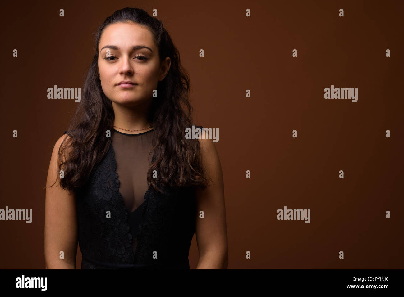 Studio shot der jungen schönen Frau gegen braunen Hintergrund Stockfoto