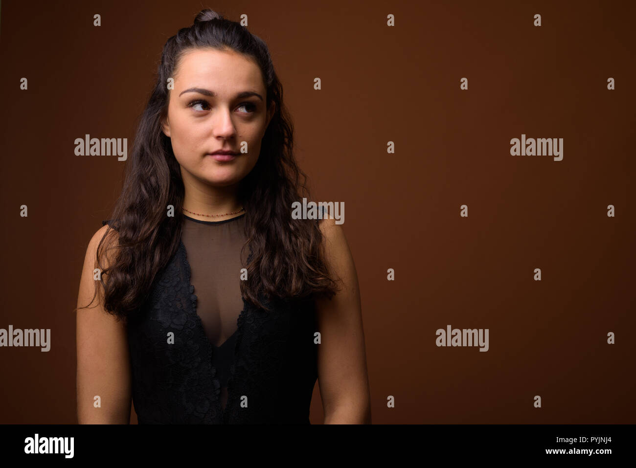 Studio shot der jungen schönen Frau gegen braunen Hintergrund Stockfoto