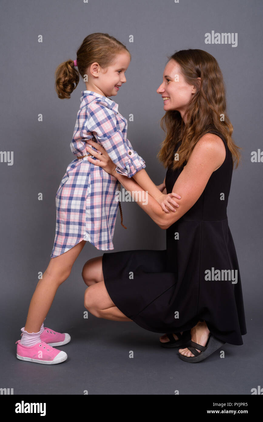 Mutter und Tochter kleben zusammen gegen grauer Hintergrund Stockfoto
