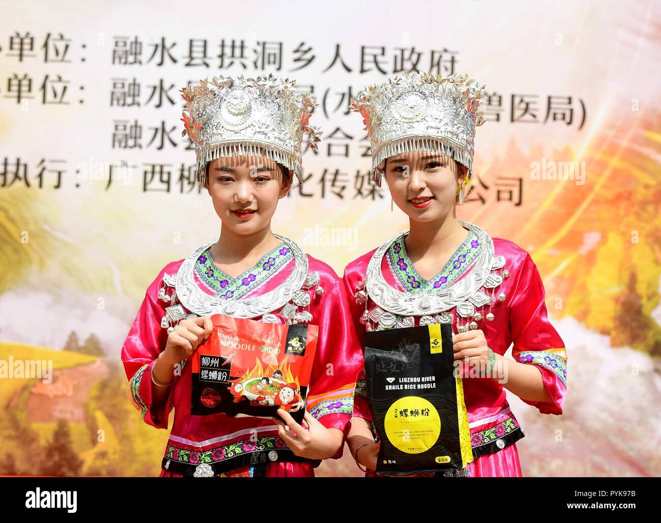 Rongshui, China Guangxi Zhuang autonomen Region. 28 Okt, 2018. Mädchen von Miao ethnische Gruppe vorhanden lokales Essen Sumpfdeckelschnecke Reisnudeln während einer Messe in Essen Kultur Gongdong Township, Rongshui Miao autonomen County, South China Guangxi Zhuang autonomen Region, Okt. 28, 2018. Die Messe war hier Sonntag Herbst Ernte zu feiern. Credit: Huang Xiaobang/Xinhua/Alamy leben Nachrichten Stockfoto