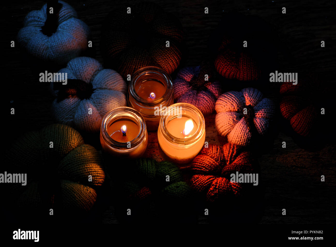 Strickmuster und Kürbis aus Garnen mit drei Kerzen in der Nacht, Kerzenschein, bunten Hintergrund, schöne handgemachte Produkt von Freizeitangebot machen Stockfoto