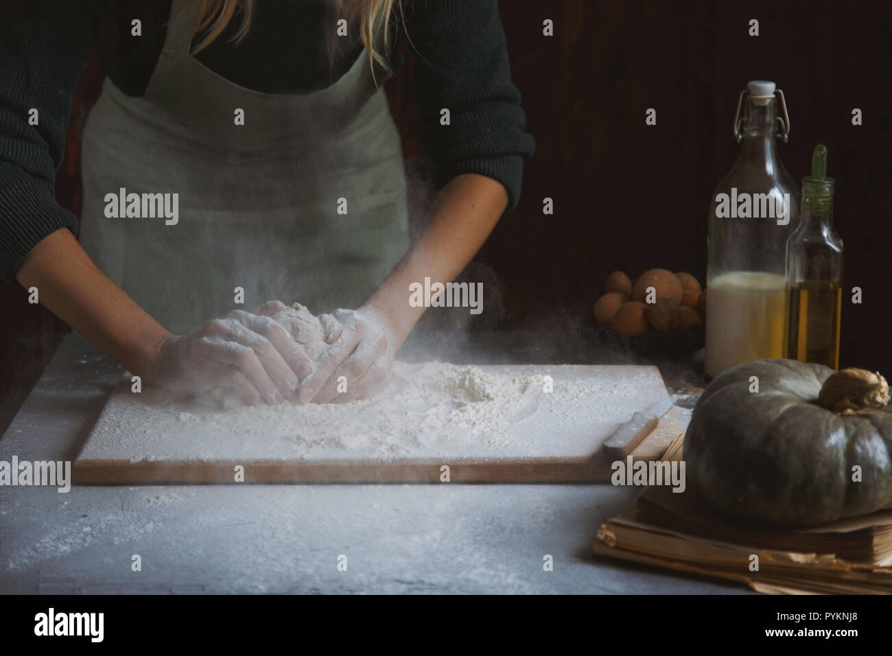 Hände kneten den Teig von Frauen. Backzutaten auf hölzernen Tisch Kürbis Milch Öl Mehl Stockfoto