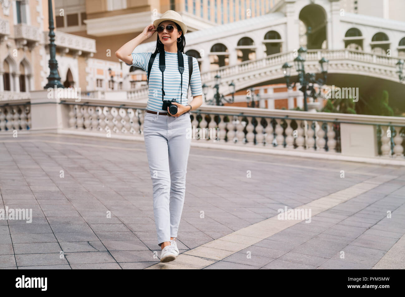Volle Länge Foto eines eleganten Reisenden zu Fuß auf die Brücke mit Strohhut auf dem Kopf. Dame Reisende mit Hut entspannende Sightseeing in Las Vegas. reise ich Stockfoto