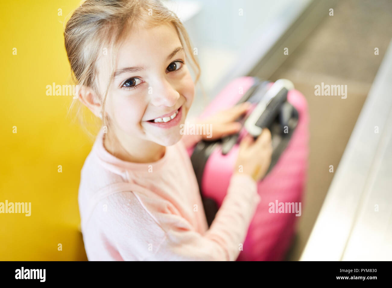Kleines Mädchen als Passagier mit Koffer beim Check in am Flughafen reist allein Stockfoto