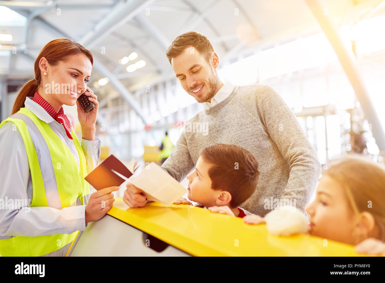 Vater und Kinder am Flughafen Check-in Schalter mit Service Agent bei der Passkontrolle Stockfoto