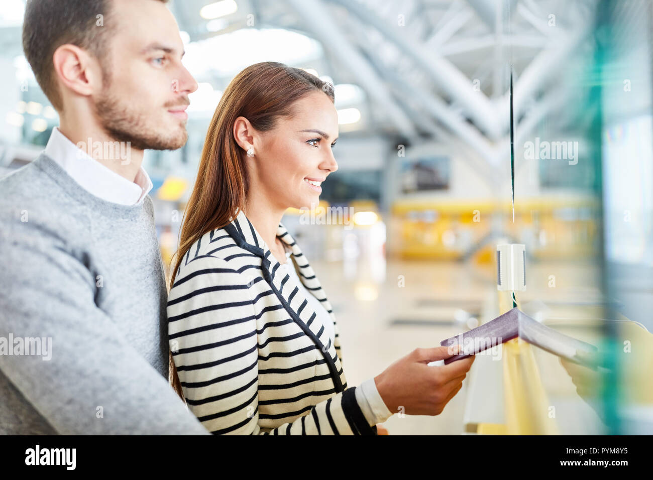 Junges Paar mit Reisepass beim Check-in-Schalter im Flughafen Terminal am Eintrag Stockfoto