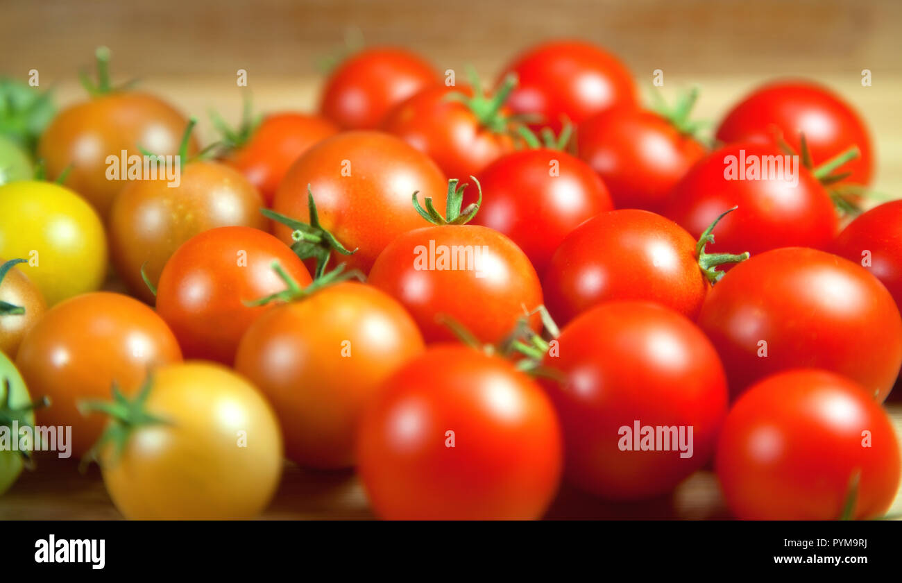 Reife und unreife Trauben Tomaten auf einer hölzernen Hintergrund Stockfoto