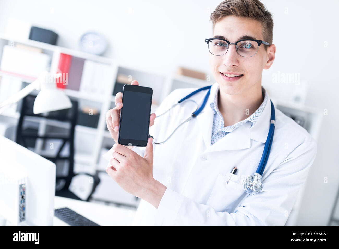 Ein junger Mann in einer weißen Robe steht im Büro und ein Telefon. Stockfoto