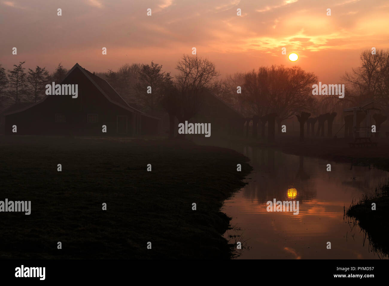 Schönes, typisch niederländischen Holzhäuser Architektur an der Sunrise moment gespiegelt auf dem ruhigen Kanal von Zaanse Schans im Norden von Amsterdam Stockfoto