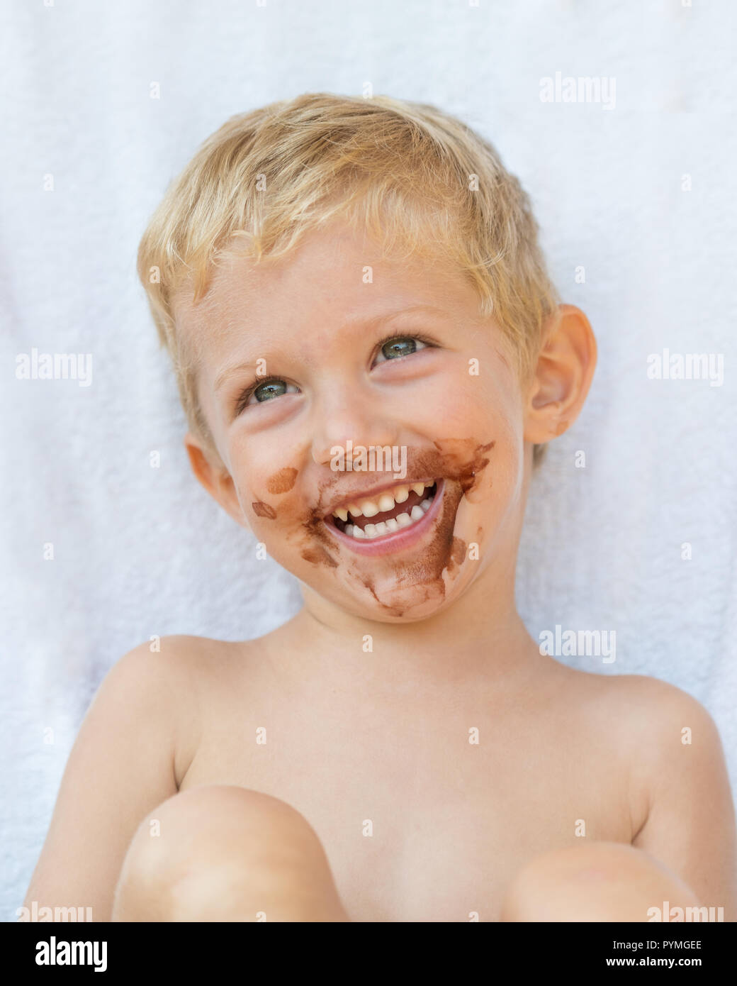 Porträt der blonde Junge mit Schokolade auf seinem Gesicht auf weißem Hintergrund, baby boy Lächeln. Stockfoto