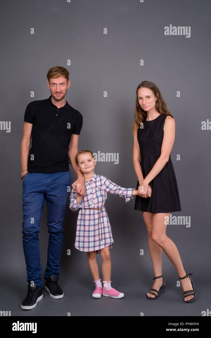 Junge, glückliche Familie kleben zusammen gegen grauer Hintergrund Stockfoto