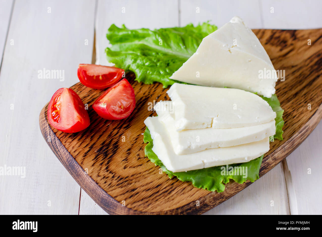 Hausgemachte Adyghe Käse mit Gewürzen auf Holzbrett mit frischem Gemüse Stockfoto