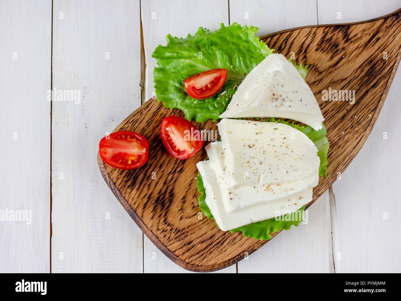 Hausgemachte Adyghe Käse mit Gewürzen auf Holzbrett mit frischem Gemüse, Ansicht von oben Stockfoto